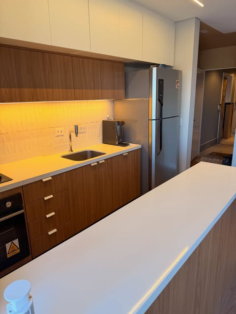 Bancada clara em cozinha com marcenaria amadeirada