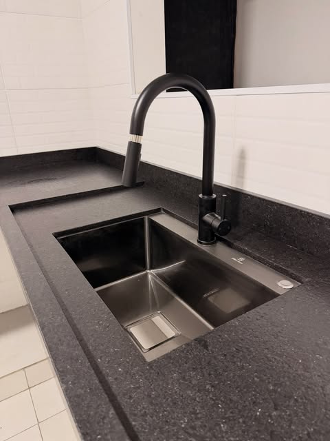 Detalhe de bancada em pedra escura com cuba de inox embutida